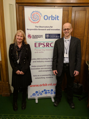 Professors Marina Jirotka of Oxford University and Bernd Stahl of De Montfort standing in front of a pull-up banner featuring information about ORBIT